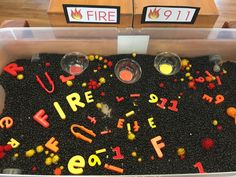 two plastic containers filled with letters and numbers on top of a wooden table next to a sign that says fire