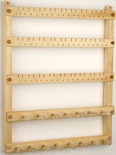 three wooden pegs are hanging on the wall with holes in each row to hold different sized pegs