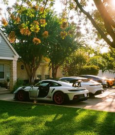 two white sports cars parked in front of a house