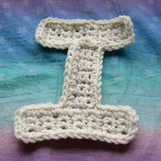 the crocheted letter t is displayed on a blanket