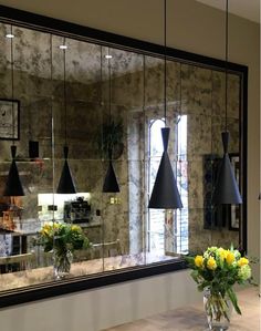 a vase filled with yellow flowers sitting on top of a table next to a mirror