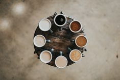 several cups of coffee are arranged on a table top with their lids down and one cup is in the middle