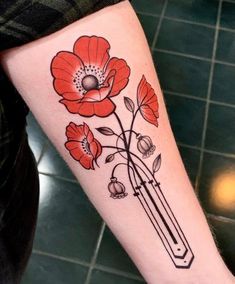 a woman's arm with red flowers on it and a pencil in the middle