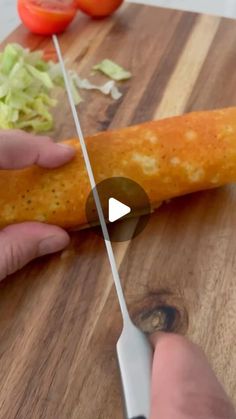 a person cutting up food on top of a wooden cutting board next to a knife