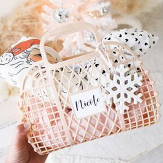 a hand holding a small basket with snowflakes on it and a name tag