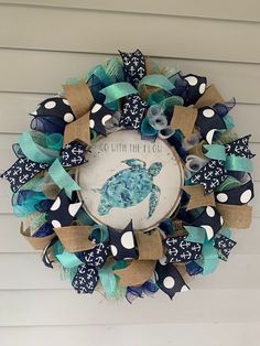 a wreath that is hanging on the side of a house with blue and white decorations