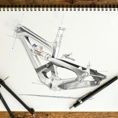 a drawing of a bicycle frame and tools on top of a wooden table next to some pens