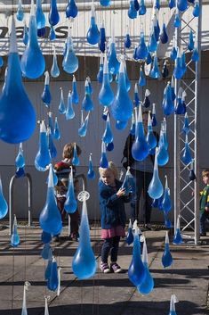 a group of children playing with blue glass raindrops hanging from the side of a building