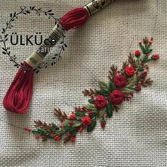 a red tasseled necklace with flowers and leaves is laying on a piece of fabric