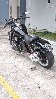 a black motorcycle parked in front of a building with a license plate on it's side