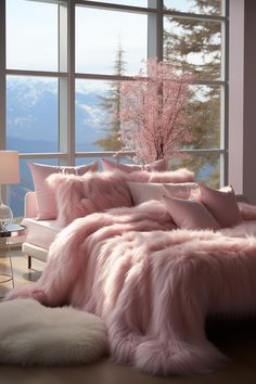 a bed with pink fur and pillows in front of a large window overlooking the mountains