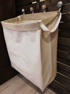 a laundry hamper hanging on the wall with three knobs attached to it's sides