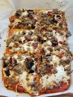 a square pizza sitting on top of a pan covered in cheese and meat toppings