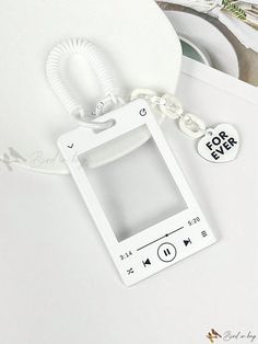 an mp3 player keychain sitting on top of a white table next to other items