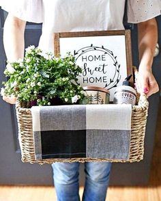 a person holding a basket with plants in it and a sign that says home sweet home