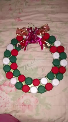 a christmas wreath made out of buttons on a bed