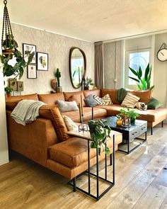 a living room filled with lots of furniture next to a wall mounted clock and potted plants