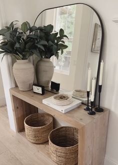 a wooden table topped with two baskets and a large mirror over it's top