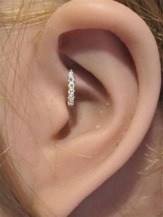 a woman's ear is shown with three small diamonds on the middle part of it