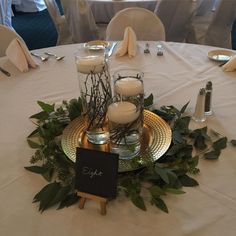 the table is set up with candles and greenery for an elegant centerpieces