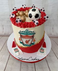 a soccer themed cake on a plate with the name liverpool in gold and red icing