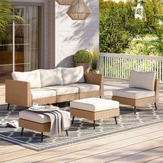 an outdoor living room with wicker furniture and white cushions on a patio area rug