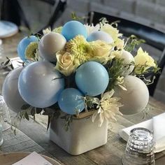 a vase filled with balloons and flowers on top of a table