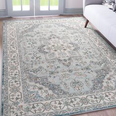 a large rug with an ornate design on the floor in front of a couch and window