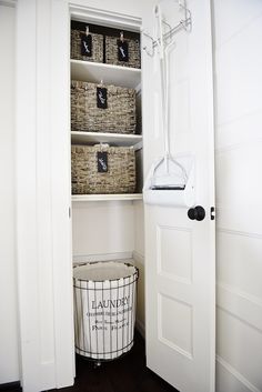 a white closet filled with baskets next to a door and a basket on the bottom shelf