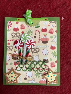 a small christmas card with scissors and candy canes on the front, sitting on a red surface