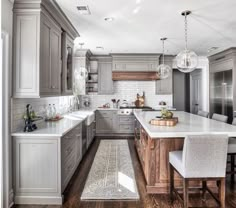 a large kitchen with wooden floors and white counter tops, along with gray cabinets on both sides