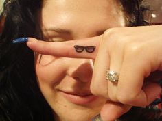 a woman with sunglasses on her face is pointing at the camera while wearing a ring