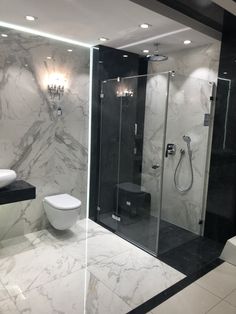 a modern bathroom with black and white marbled walls, flooring, and a walk in shower