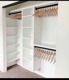 an empty closet with white shelves and wooden hangers