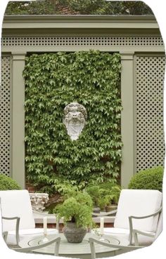 an outdoor area with chairs and a table in front of a trellis covered wall