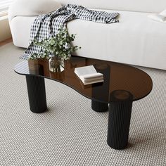 a glass table sitting on top of a carpeted floor next to a white couch