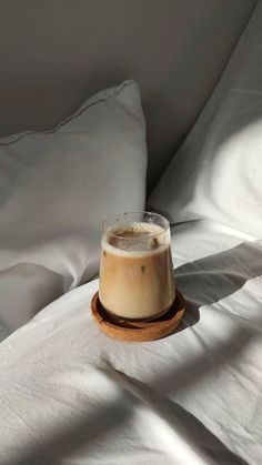 there is a beverage on the bed with white sheets