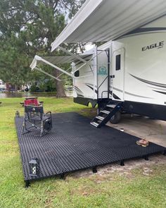 an rv parked on the grass with its awning open and stairs up to it