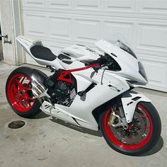 a white and red motorcycle parked in front of a garage