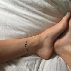 a person laying in bed with their feet up on the pillow and one has a small tattoo on it