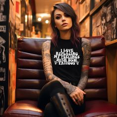 a woman sitting in a chair with tattoos on her arm and leg, wearing a black shirt