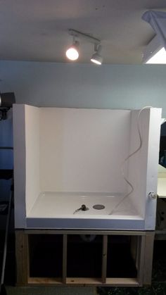 an empty white box is sitting in the middle of a room with some lights on