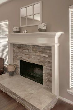 an empty living room with a fireplace and large windows