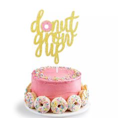 a pink cake with donuts on it and the words donut trip spelled in gold glitter