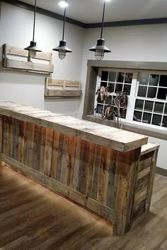 a large wooden counter sitting in the middle of a room next to two lights and a window