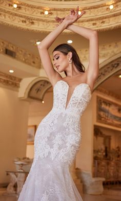 a woman in a white wedding dress posing for the camera with her arms up and hands behind her head