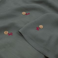 two pieces of clothing with red and gold embroidered designs on them, laying next to each other