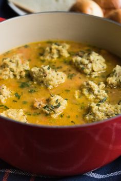 a red pot filled with soup next to bread