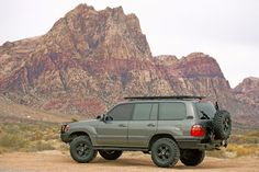 an suv parked in the desert with mountains in the background