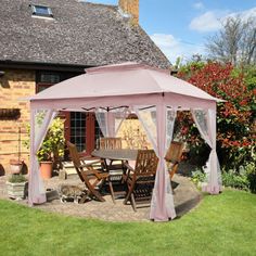 a pink gazebo sitting on top of a lush green field next to a house